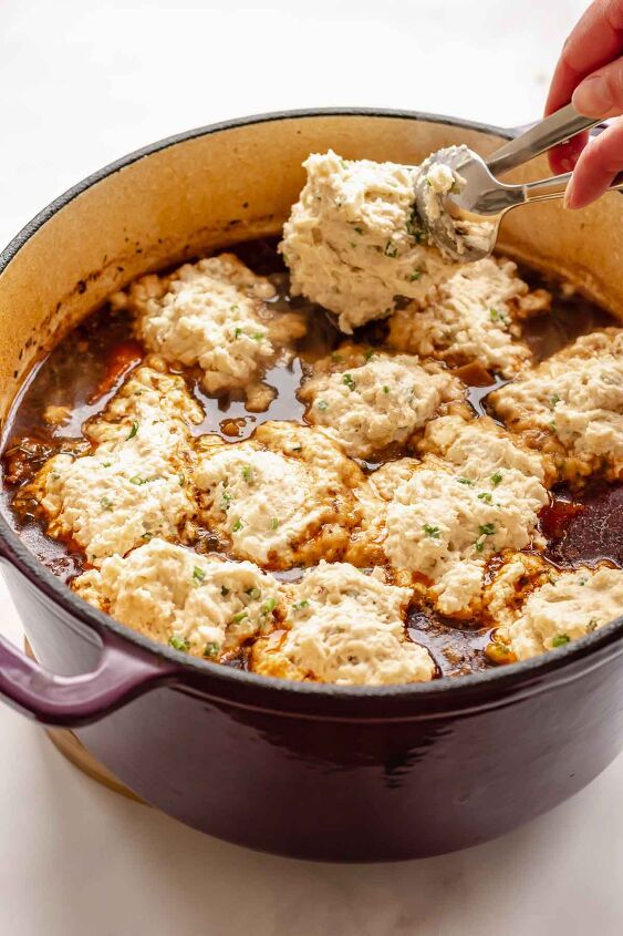 irish beef stew with cheddar dumplings, A spoon drops a raw dumpling batter into a pot of stew