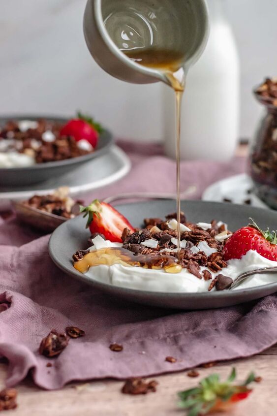 dark chocolate granola, Maple syrup pouring over yogurt and chocolate granola in a bowl