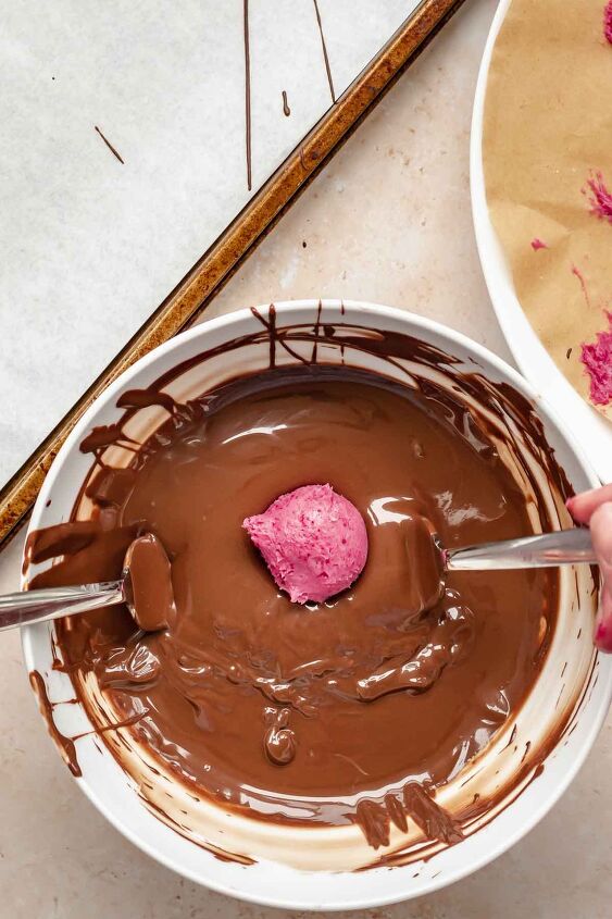 chocolate raspberry truffles with raspberry filling, A truffle in a bowl of melted chocolate with two forks underneath