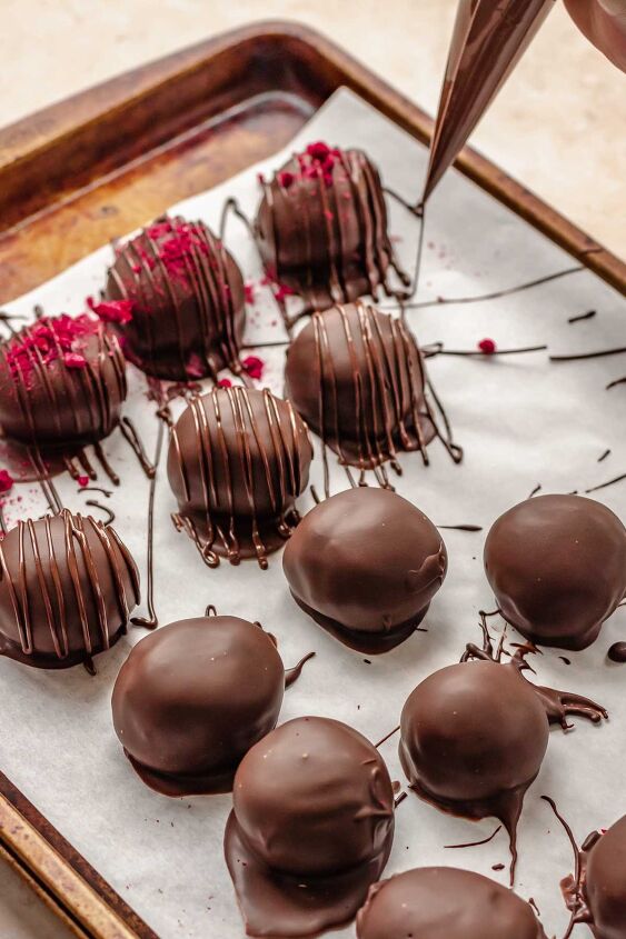 chocolate raspberry truffles with raspberry filling, A piping bag pipes drizzles of chocolate over dipped truffles
