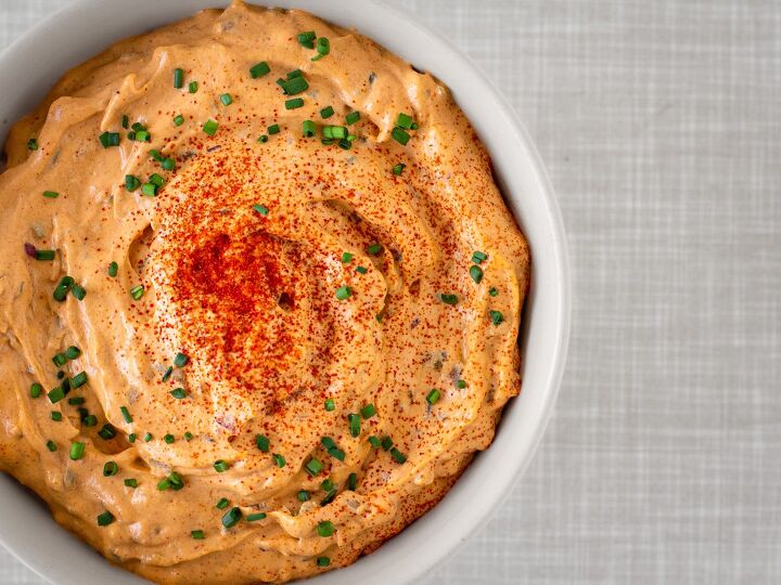 Homemade vegan Liptauer cheese spread in a bowl topped with chives and paprika powder