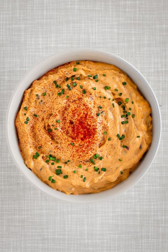 Homemade vegan liptauer cheese spread in a bowl topped with chives and paprika powder