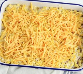 crack corn casserole, Close up of crack corn casserole in a white rectangle dish with shredded cheese sprinkled on top before going into the oven