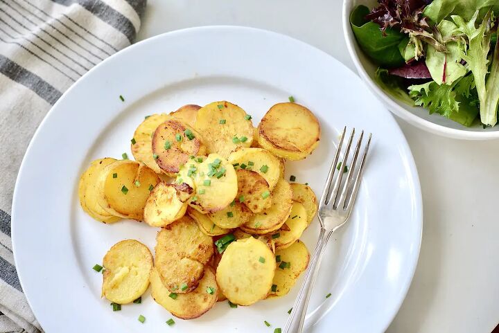 easy german fried potatoes bratkartoffeln, German fried potatoes on plate with fork and green salad on the side