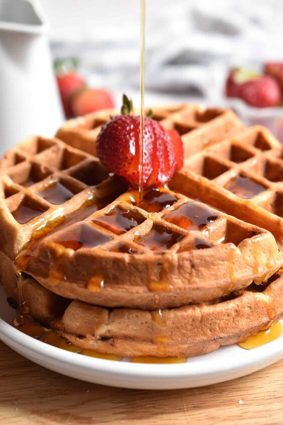homemade strawberry waffles so easy, Maple syrup is being poured on a stack of strawberry waffles