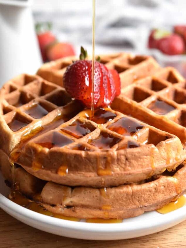 homemade whole wheat buttermilk waffles, Maple syrup is being poured on a stack of strawberry waffles
