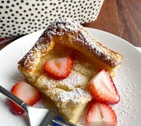 swedish oven pancake, A square slice of Swedish Oven Pancake topped with sliced strawberries on a white plate with a fork