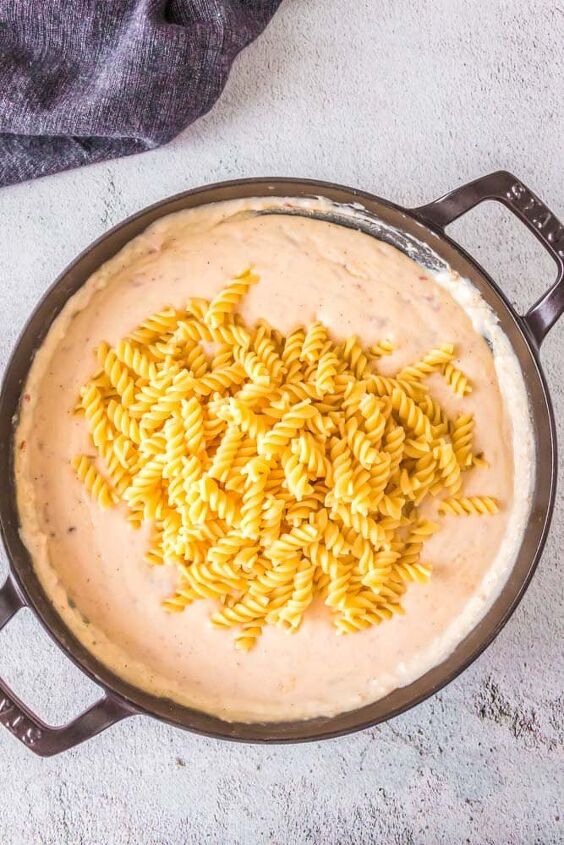 cheesy baked bechamel pasta, Pasta being added to the creamy bechamel sauce