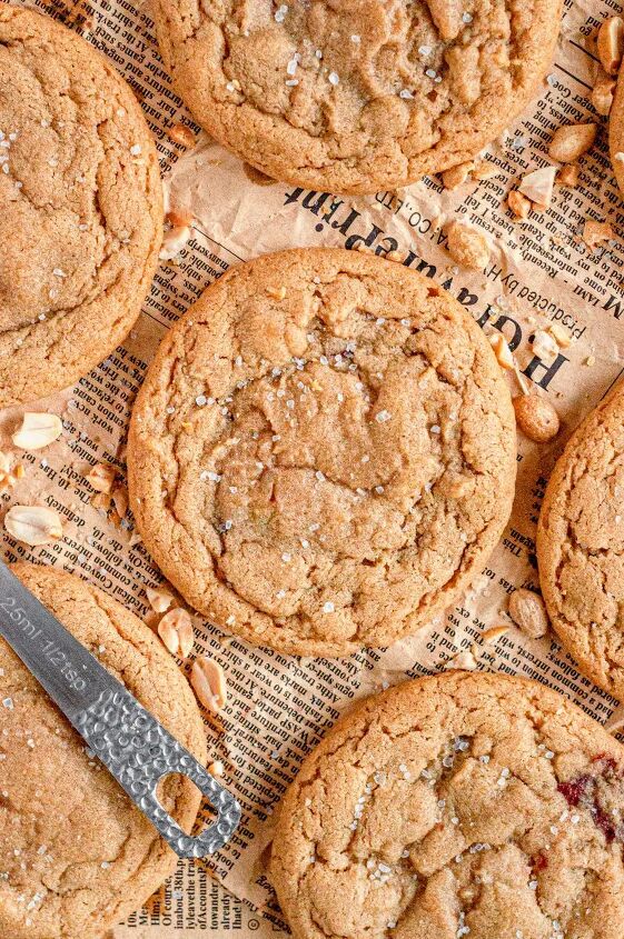peanut butter and jelly cookies gluten free dairy free, Light golden brown peanut butter cookies topped with white coarse sea salt They are surrounded by chopped peanuts and sitting on a piece of brown newspaper