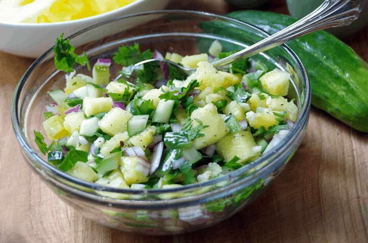 bowl of cucumber salsa with pineapple in glass bowl on cutting board