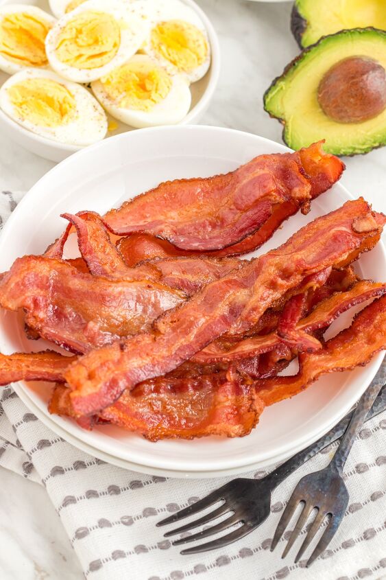 how to cook bacon in the air fryer, bacon on a plate on the table with boiled eggs and avocado
