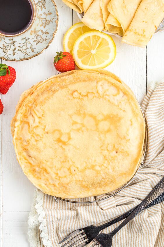 parisian crepes will make you the star of brunch, Parisian Cr pes stacked on table with cutlery lemon slices and strawberries