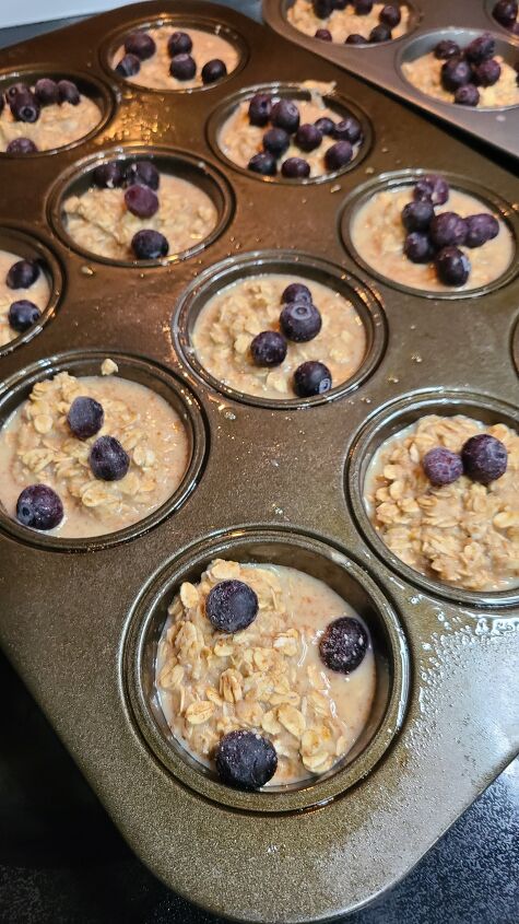 baked blueberry oatmeal cups meal prep friendly, Two muffin tins filled with unbaked baked oat cups topped with blueberries