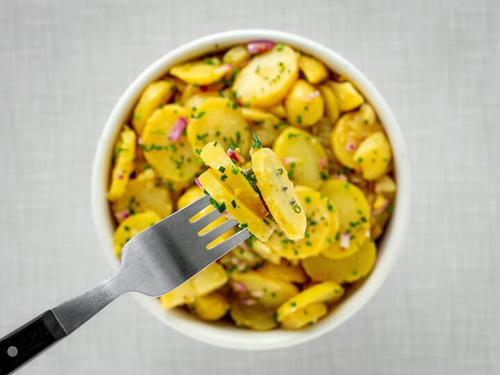 austrian potato salad, A fork with potato salad on it in the background a bowl filled with potato salad