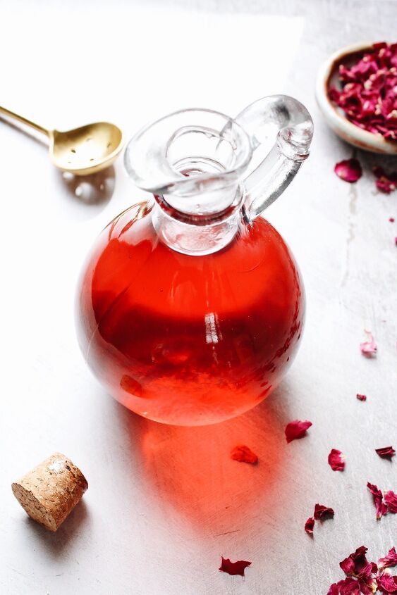 rose simple syrup, rose simple syrup in a glass jar with rose petals scattered around