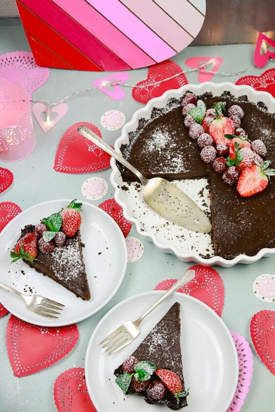 chocolate coffee ganache with raspberries, Chocolate cake slices sitting on white plates with Valentine s paper mache and topped with fresh berries and mint with a light dusting of powered sugar