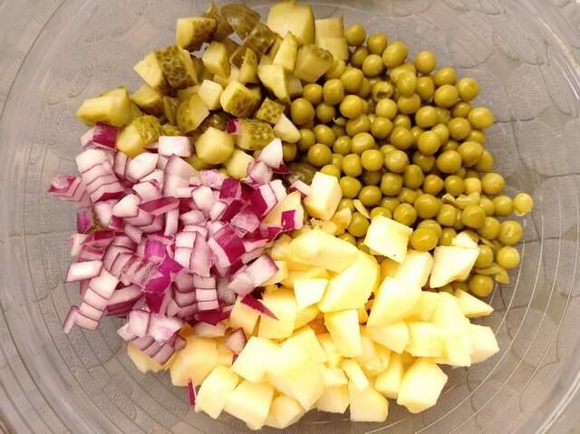 vegan potato salad, Green peas chopped apple red onion and pickles in a glass bowl