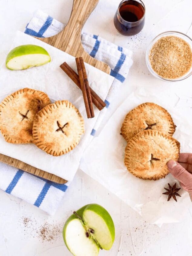 easy vegan hand pies apple, Vegan Apple Hand Pies four on a white backdrop with a cutting board cinnamon sticks apple slices and star anise