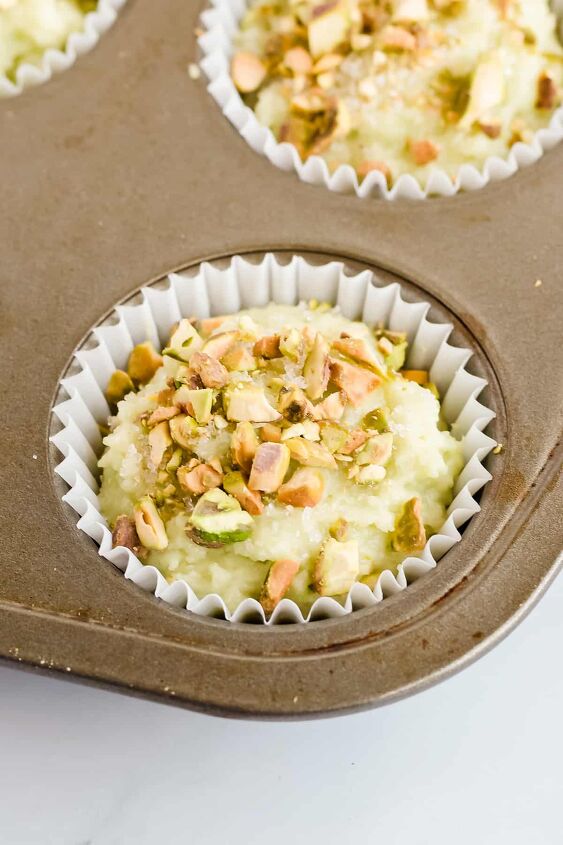 pistachio pudding muffins, Close up of raw muffin in tin with coarse sugar and chopped pistachios on top