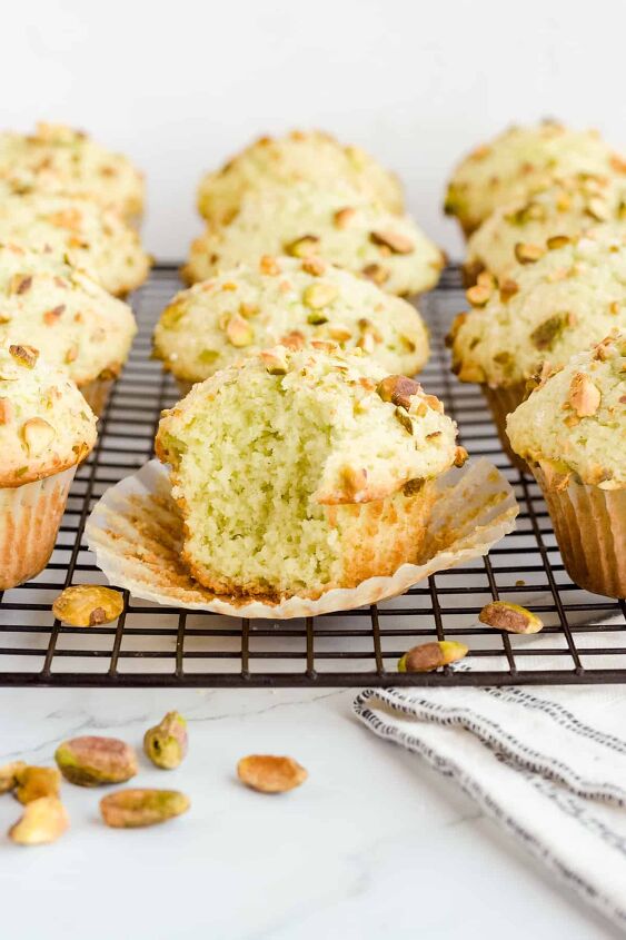 pistachio pudding muffins, Pistachio pudding muffins on black wire rack with a bite taken out of front muffin Roasted pistachios are scattered on counter in front