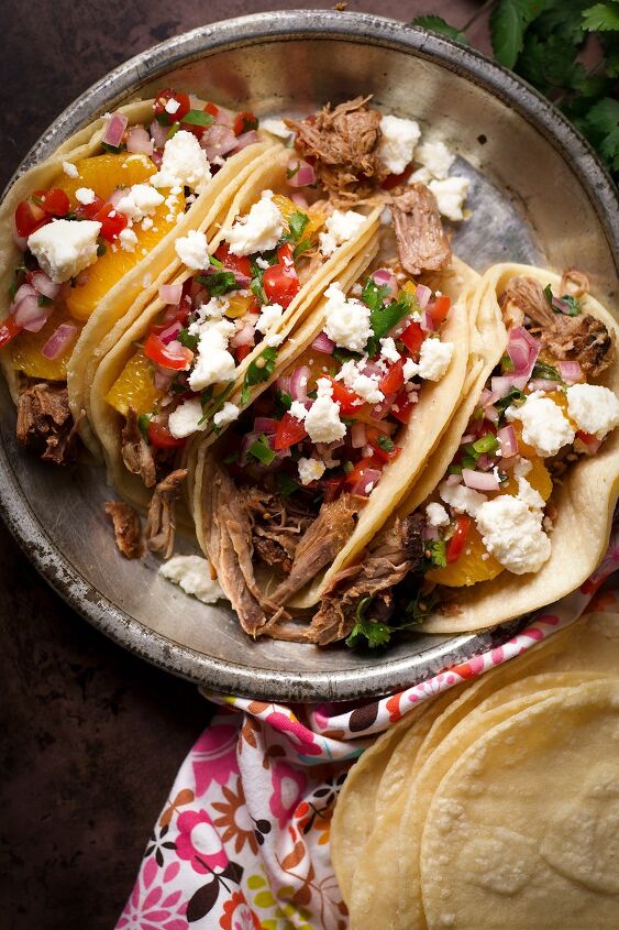 camping tacos shredded pork with pico de gallo, Four shredded pork tacos with orange slices pico de gallo and crumbled queso fresco on a tin plate