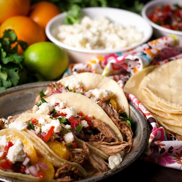 camping tacos shredded pork with pico de gallo, Four shredded pork tacos with orange slices pico de gallo and crumbled queso fresco on a tin plate
