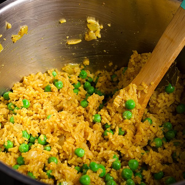 Stirring a pot of Indian Rice with peas