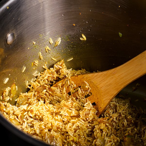 Stirring rice into Indian spices while cooking Indian Rice