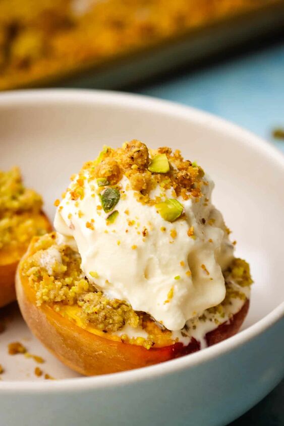 roasted peaches with pistachio crumble, Roasted halved peaches in a bowl with a scoop of vanilla ice cream and pistachio crumble