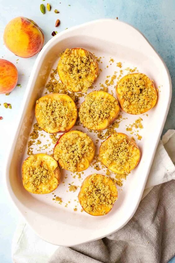 roasted peaches with pistachio crumble, Roasted peach halves topped with pistachio crumble in a baking dish