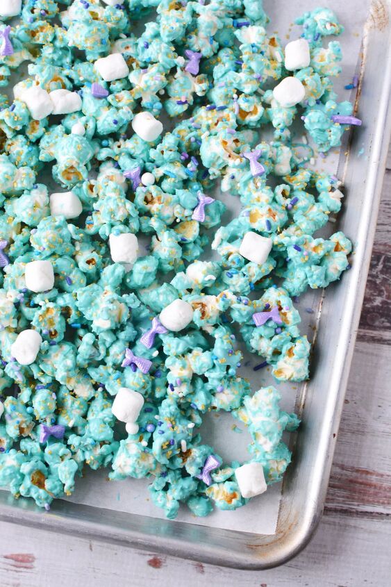 Coated blue popcorn with sprinkles and marshmallows on a baking sheet