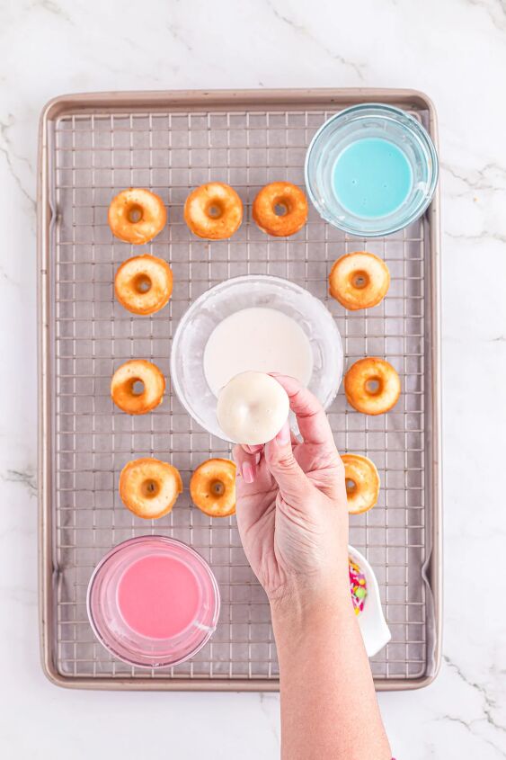 bright and delicious mini donuts with colorful glaze little fairy do, Adding glaze to little donuts on a rack