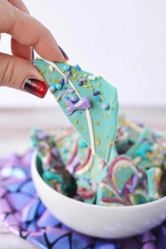 sparkly mermaid bark candy for an easy under the sea sweet, Holding a piece of mermaid bark with the bowl in the bacground