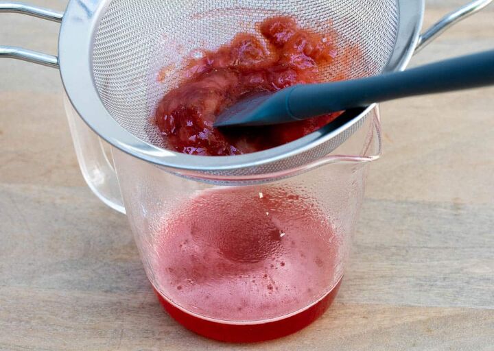 strawberry mimosa, straining strawberry syrup into glass measuring cup