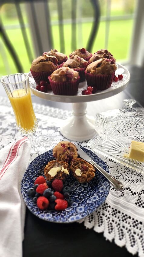 best cranberry walnut muffin recipe with orange marmalade, cranberry walnut muffins on a white pedestal dish with orange juice and butter dish on the side