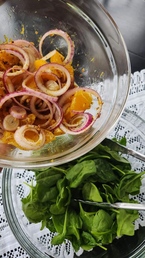 scallop salad recipe with orange honey walnut vinaigrette, Glass bowl with spinach with another glass bowl on top with oranges onions and dressing ready to be added