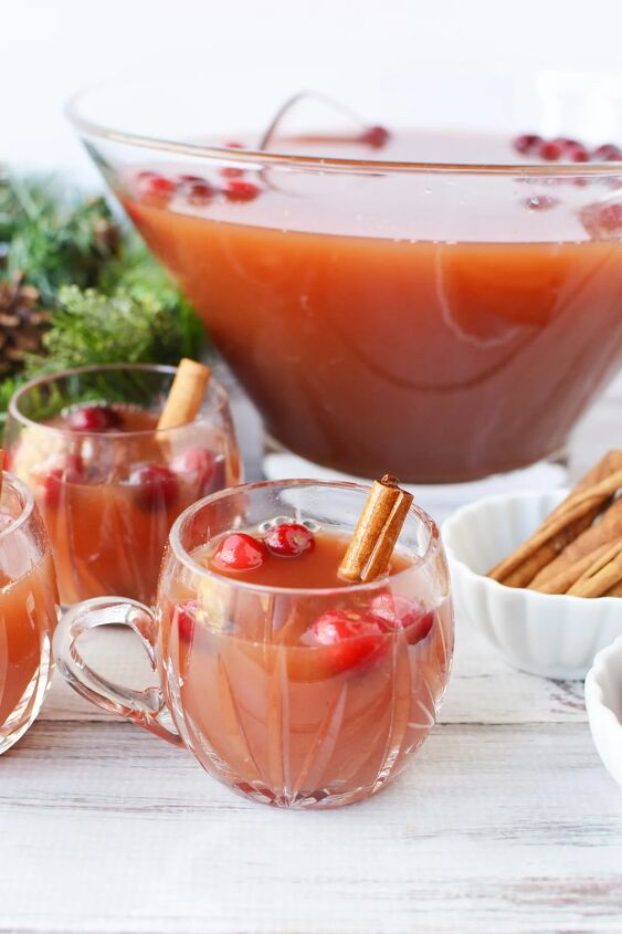 cranberry and cinnamon christmas punch recipe, Mugs of punch with cranberries and cinnamon sticks next to the bowl of punch