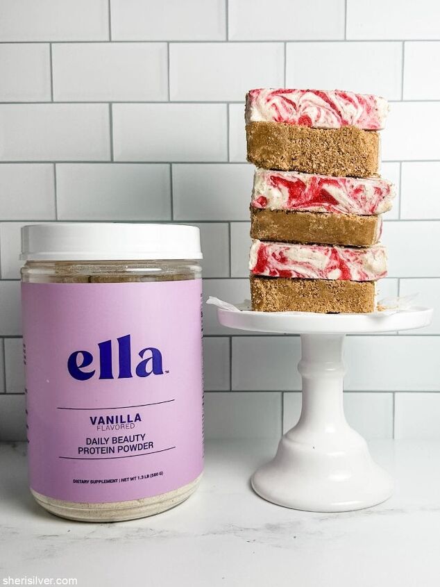 high protein strawberry cottage cheese ice cream bars, strawberry cottage cheese ice cream bars on a white cake stand next to a jar of Ella protein powder