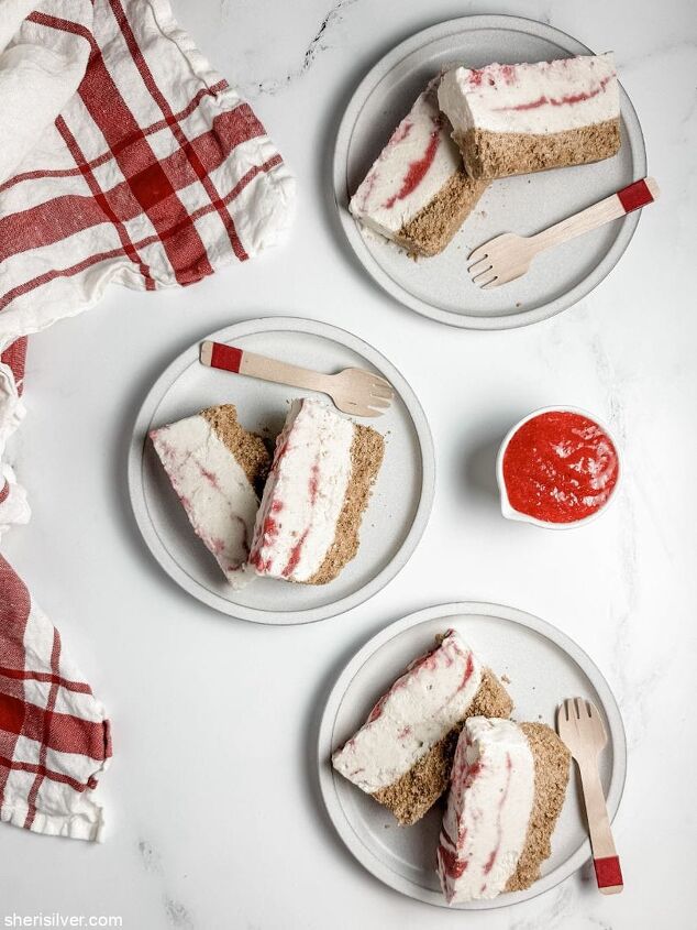 high protein strawberry cottage cheese ice cream bars, strawberry cottage cheese ice cream bars on white plates with a bowl of strawberry puree and a red and white linen napkin