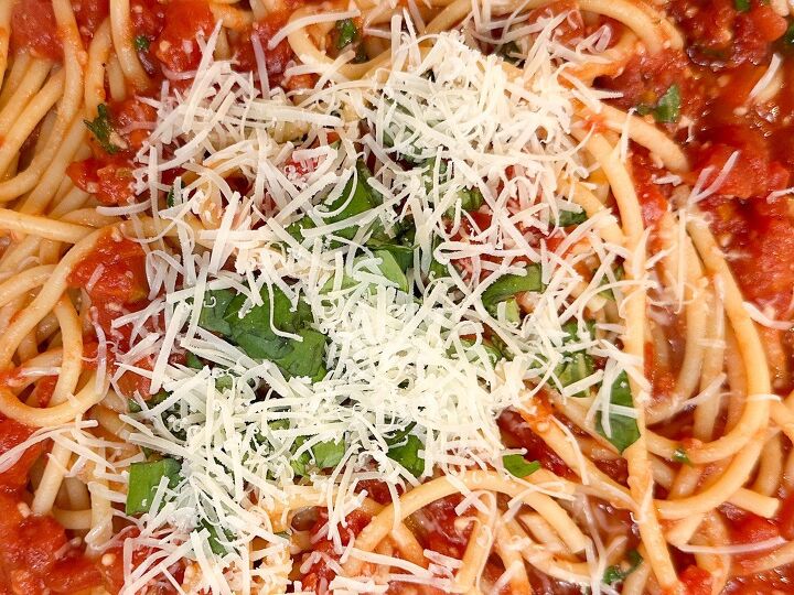 simple bucatini pomodoro pasta recipe, finished bucatini pomodoro garnished with grated parmesan cheese a chopped fresh basil