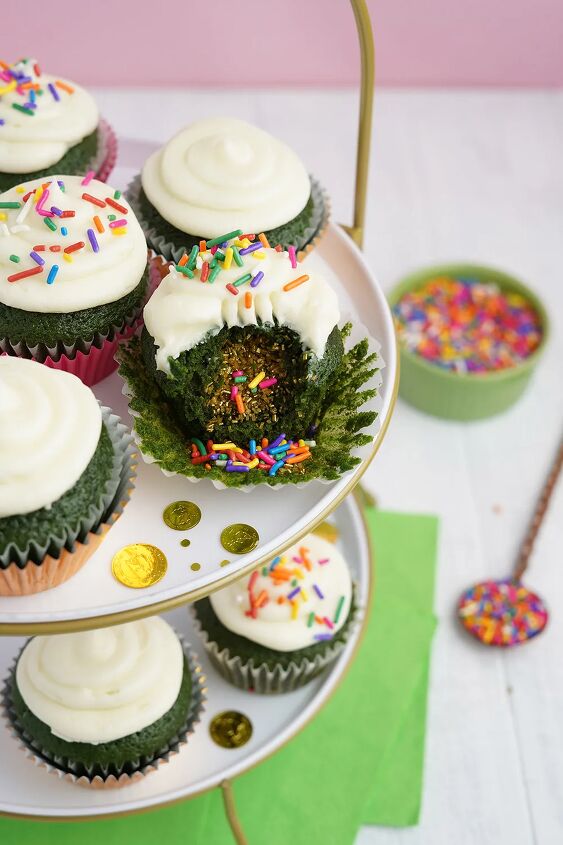 stuffed green velvet cupcakes, Cupcakes on a tray One of them has a bite taking out showing the surprise filling of sprinkles