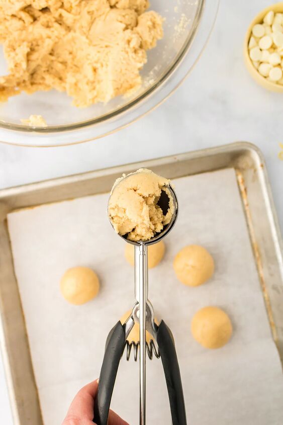light and creamy lemon oreo truffles, Oreo balls in a cookie scoop above a baking sheet