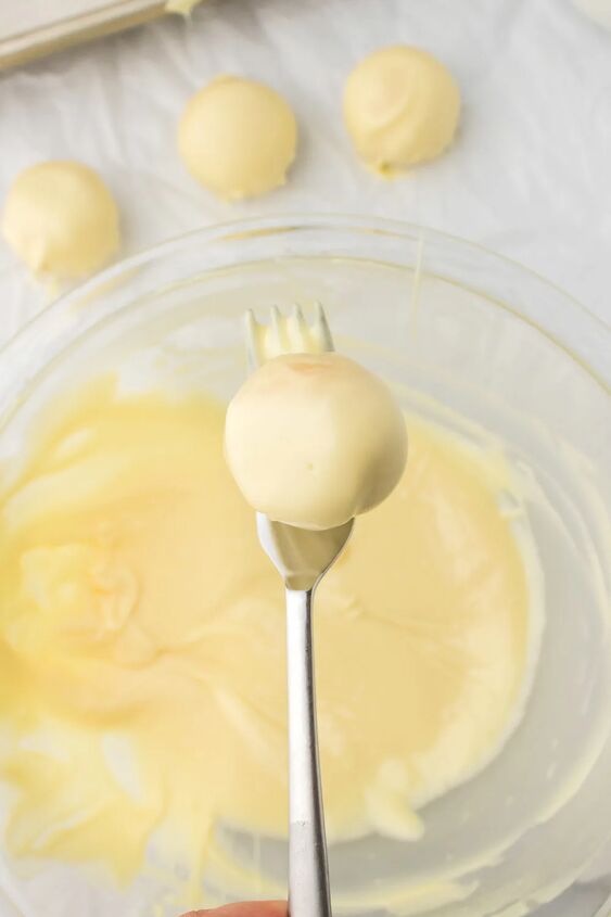 light and creamy lemon oreo truffles, Dipping an oreo ball into coating with a fork