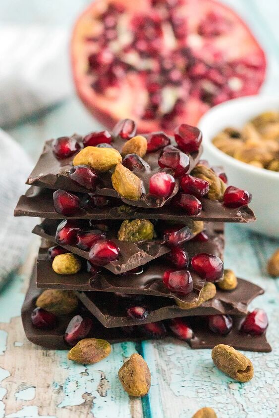 chocolate pomegranate bark with pistachios, Chocolate pistachio bark pieces stacked with pomegranate in the background