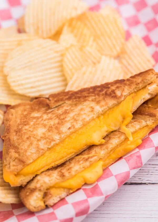 the secret to the perfect grilled cheese sandwich, grilled cheese served as a meal with ruffled chips on a dish lined with checkered red and white wax paper