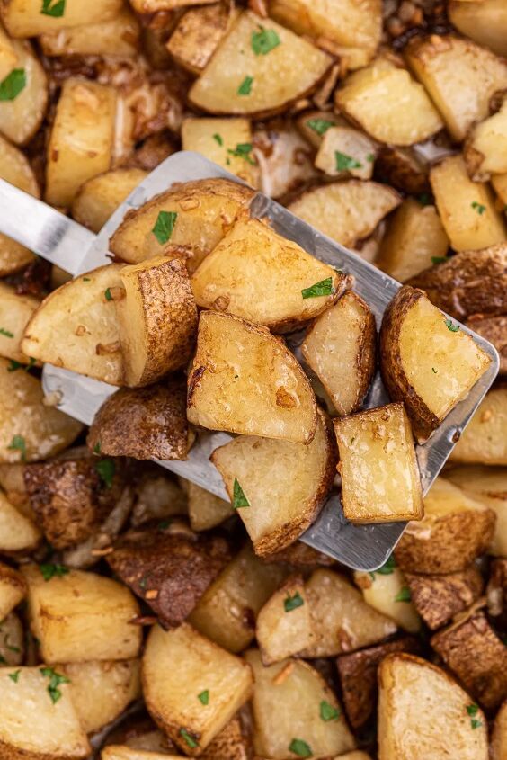 easy roasted potatoes made with one magic packet, roasted potatoes some resting on a spatula over a large dish of potatoes