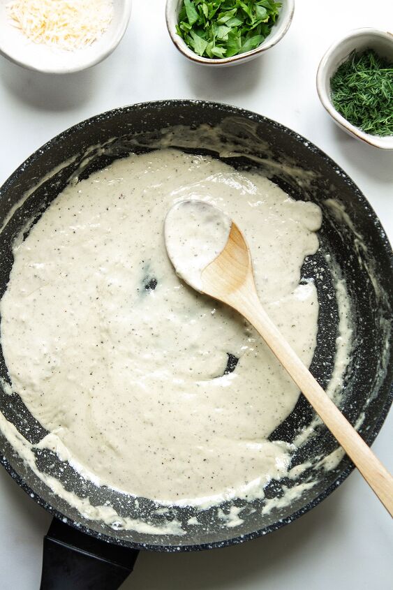 creamy white wine pasta sauce, A frying pan on a white background containing the sauce with cream and seasoning added