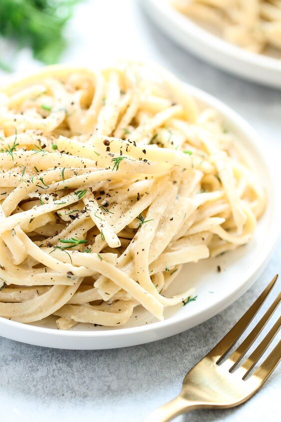 creamy white wine pasta sauce, A plate of pasta toss in creamy white wine sauce on a pale blue background