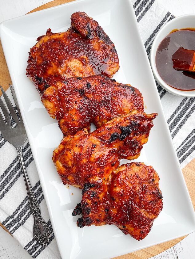 air fryer bbq chicken thighs boneless or bone in, air fryer bbq chicken thighs on a white platter next to bowl of bbq sauce
