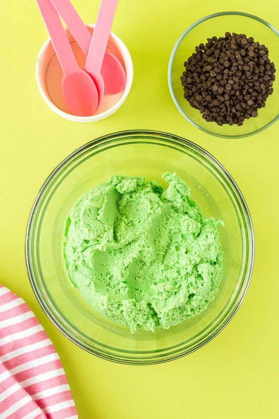 mint chip edible cookie dough, Green cookie dough in a mixing bowl next to chips and pink spoons
